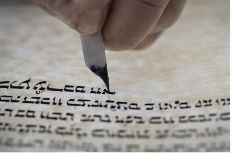 Sofer writing parshiyot by hand on klaf